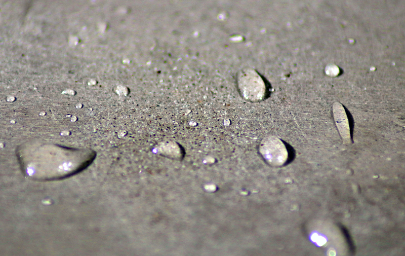 Vägg i Ljusgrå microcement – närbild, yta, vattendroppar