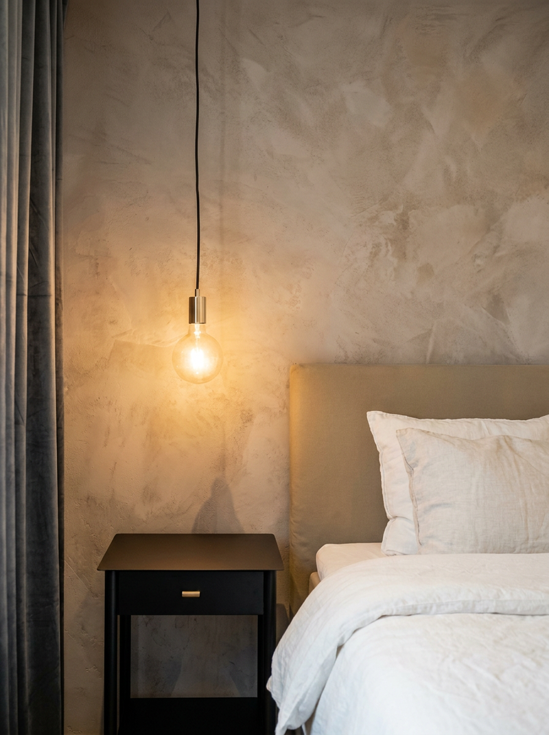 Vägg i Gråbeige microcement – sovrum, pendellampa, sänggavel