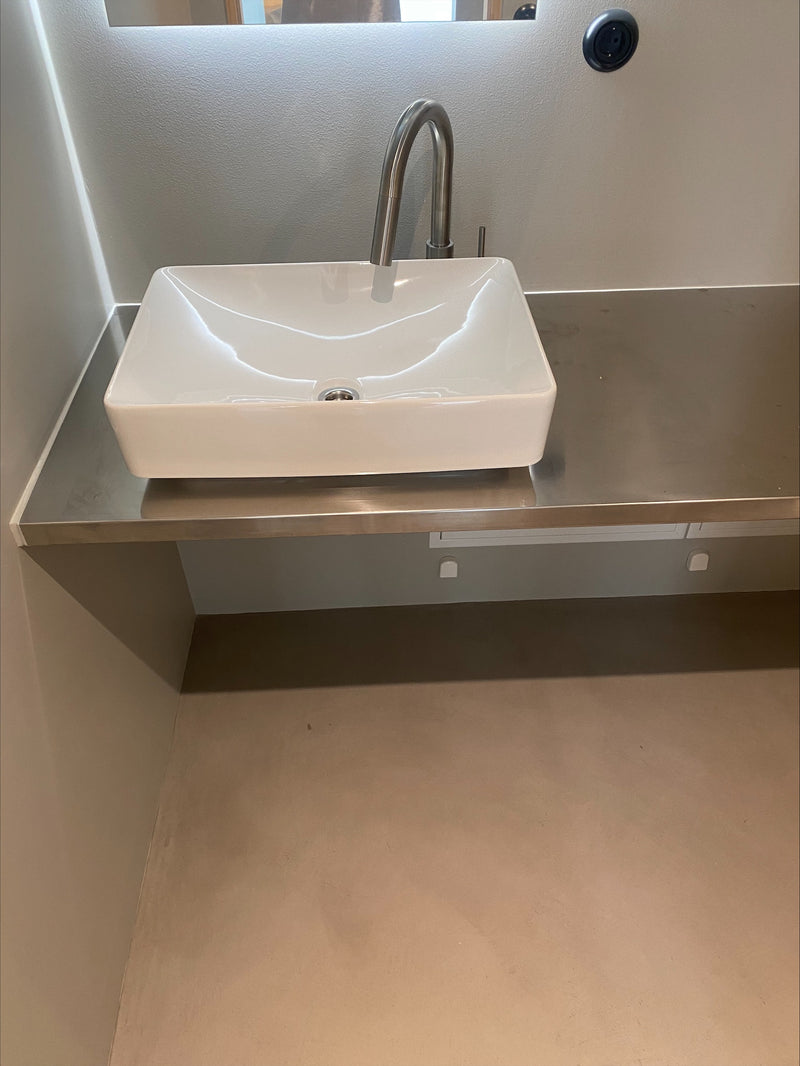 Badrum i gråbeige microcement – handfat, kran, närbild