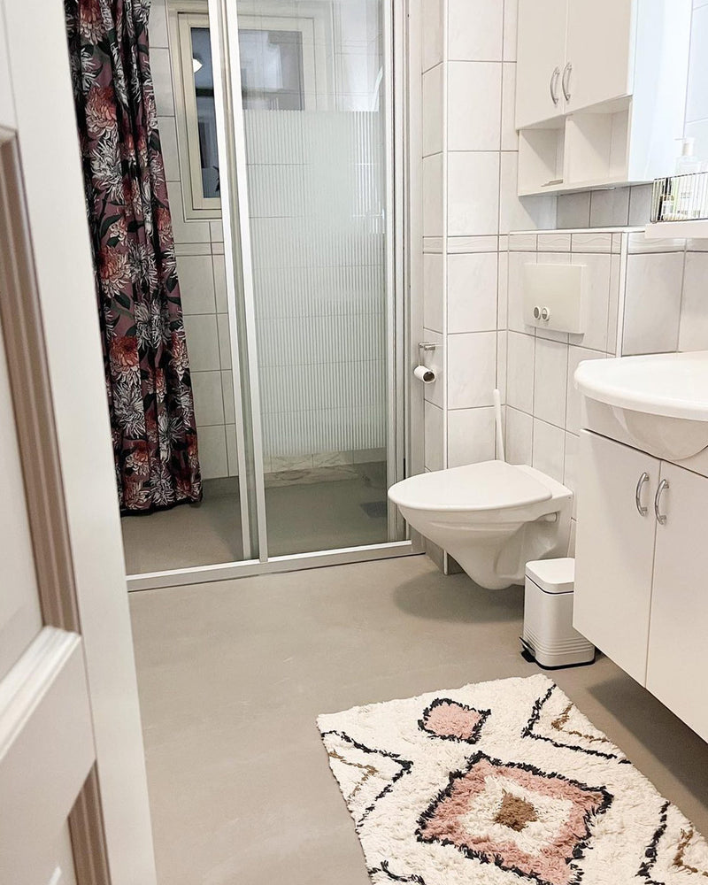 Badrum renoverat med ljusgrå microcement – toalett och matta - efter